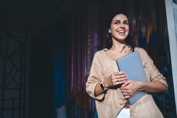 Cheerful female freelancer with modern technology laughing at urbanity during break from remote...