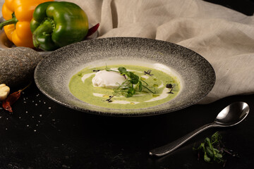Creamy spinach soup with poached egg, garnished with cream, aioli sauce and pea sprouts microgreen