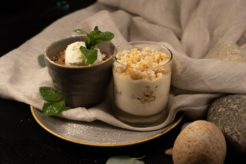 Dessert granola with a scoop of vanilla ice cream decorated with mint leaves. Curd dessert with yoghurt in a transparent glass.