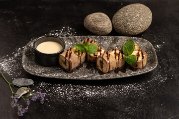 Dessert of Asian cuisine - sweet sushi roll in chocolate crepe with vanilla sauce.