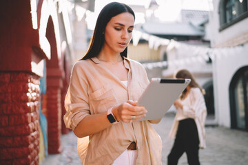 Caucasian female user browsing banking website for checking delivery price connected to 4g wireless on digital tablet, millennial woman reading news while networking text publication via touch pad