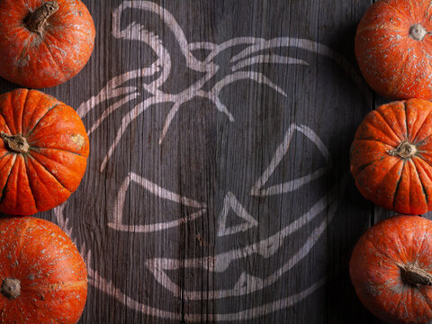 Dark wooden background with Jack's lantern image and Decorative pumpkins on the edges. Happy Halloween concept. copy space