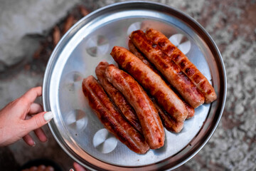 juicy grilled sausages on an iron tray. Delicious high-calorie food. Oktoberfest