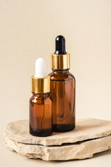 Naklejka premium Two brown bottles of cosmetics on a natural beige background. Stone podium. Front view.