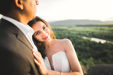 Wedding couple on the nature is hugging each other. Beautiful model girl in white dress. Man in suit