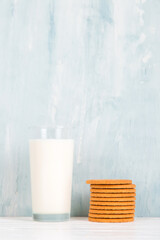 A glass of milk and cookies on the table, on a blue background, minimalism. Copy space.