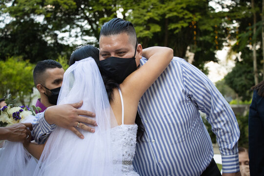 Personas abrazándose en una boda durante la pandemia, llevando máscaras médicas protectoras para protegerse contra el coronavirus
