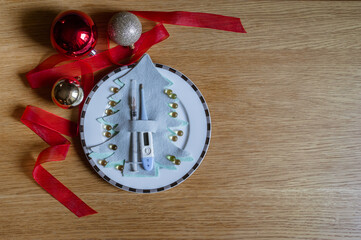Winter medicine background, thermometer and syringe. Omega-3 fish oil capsules on a plate on a wooden background with a Christmas tree. Food supplement as a gift from Santa Claus. 
