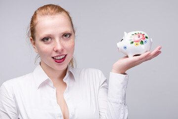 Young red haired woman with her piggy bank / porcelain bank