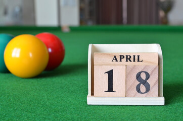 April 18, number cube with balls on snooker table, sport background.