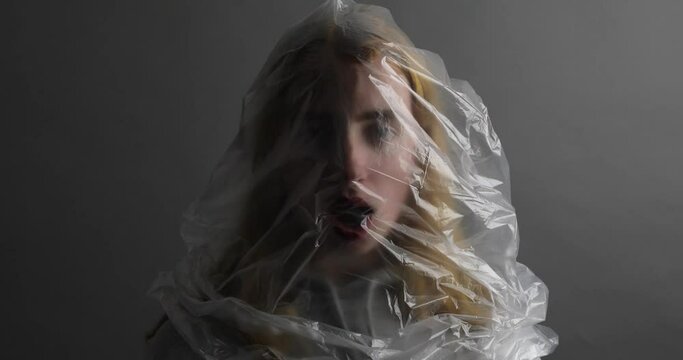 junge Frau mit Plastikt&uuml;te &uuml;ber dem Kopf versucht zu atmen