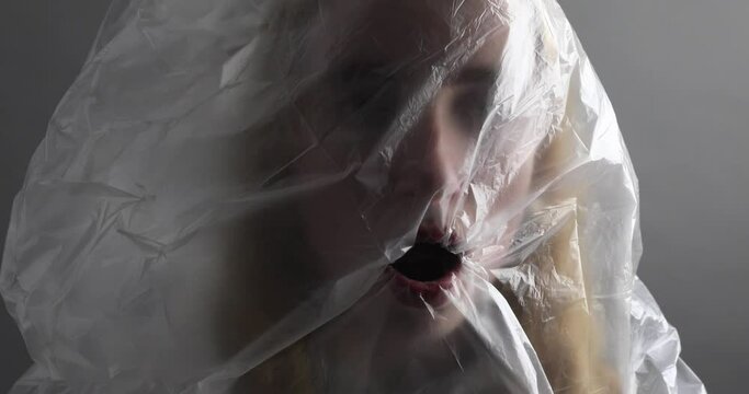junge Frau mit Plastikt&uuml;te &uuml;ber dem Kopf versucht zu atmen