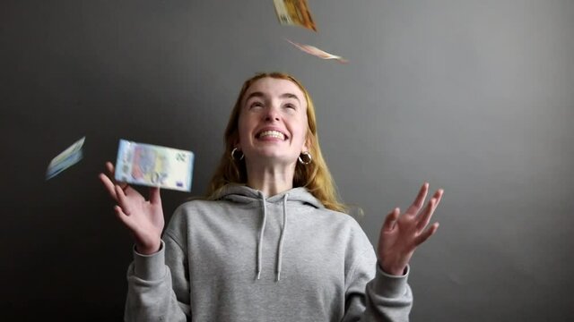junge Frau wirft Geld in die Luft und freut sich