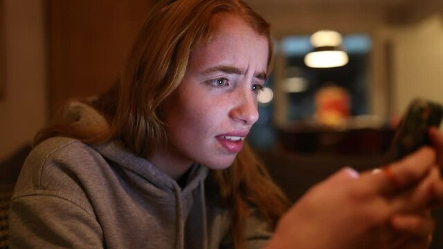 junge Frau schreibt w&uuml;tend auf ihrem Smartphone, das Gesicht wird vom Display angeleuchtet