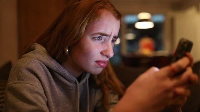 junge Frau schreibt w&uuml;tend auf ihrem Smartphone, das Gesicht wird vom Display angeleuchtet