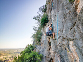 Climber with harness on huge rock