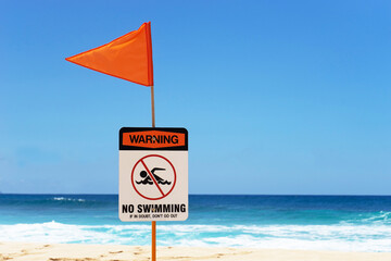 No Swimming Warning Sign with Orange Flag on the Beach
