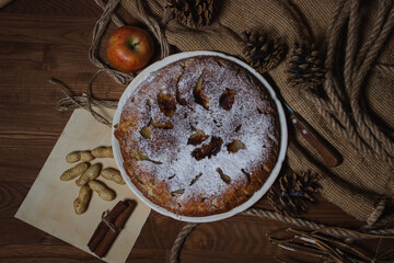 Homemade pie. Apple pie sprinkled with icing sugar. Pie on an autumn background. Autumn pastries