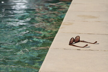 lunette de soleil posé sur le bord d'une piscine