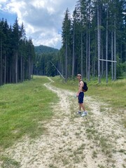 The man on the road in the forest. The guy is walking in the forest on the  road. the man is hiking in the mountains