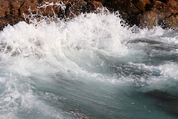 Waves break on rocks on the seashore. Clean foamy water on a stones, sea storm