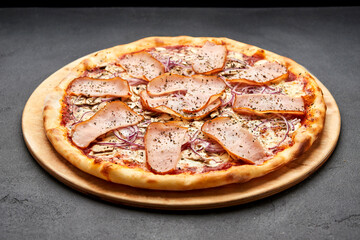 Delicious Italian Pizza with ham, onions and mozzarella cheese on dark background