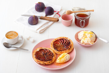 Homemade puff pastry fig tarts with vanilla and honey mascarpone - Gordon Ramsey recipe. White wooden table background.