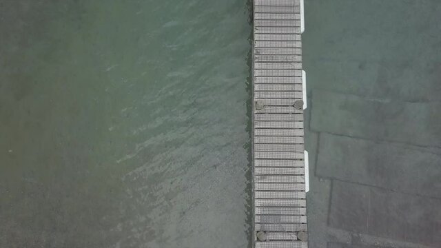 Aerial overhead shot of narrow wooden jetty over turquoise water