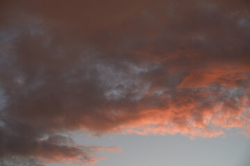 Beautiful evening blue sky at sunset with flaming bright light clouds. A warm summer evening at sunset.