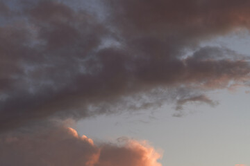 Obraz premium Beautiful evening blue sky at sunset with flaming bright light clouds. A warm summer evening at sunset.