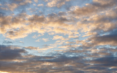 Beautiful evening blue sky at sunset with flaming bright light clouds. A warm summer evening at sunset.