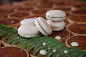 white delicate lowly macaroons on a wooden background. The pastel tone of the cream inside the French cookies