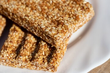 Sesame seed kozinaki on a white plate. Eastern sweetness sesame seeds in caramel