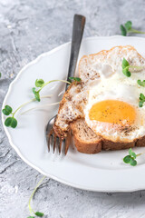 Hot toasts with fried eggs and herbs on light background