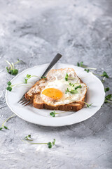 Hot toasts with fried eggs and herbs on light background