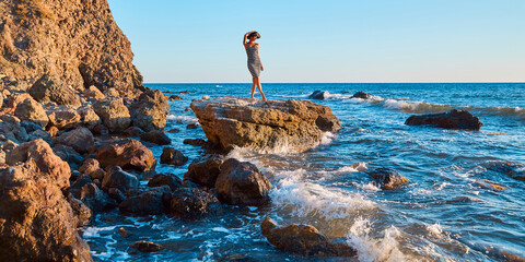 Pretty woman posing on rock. Rocky coastline and sharp cliff. Vacation time. Summer holiday and...