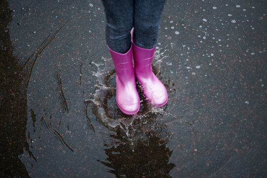
shiny pink rubber boots in a puddle
