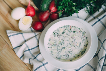 Traditional Russian summer cold soup okroshka with kefir in a bowl on a wooden background. View from above. Copy space.