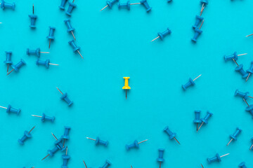 Yellow push pin in the center of blue push pins as a concept of loneliness. Conceptual photo of solitude.