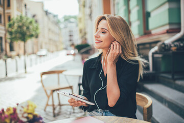 Cheerful woman with closed eyes enjoying positive audio novel from digital tablet, happy Caucasian...