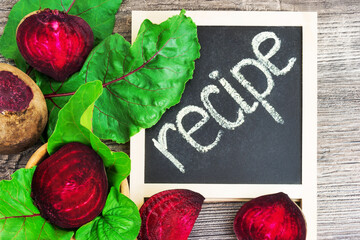 Top view at fresh organic beets with green leaves with recipe on wooden rustic background. Close up view. - 378602357