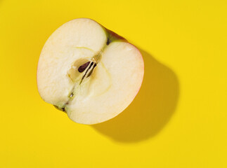 half of apple on yellow background