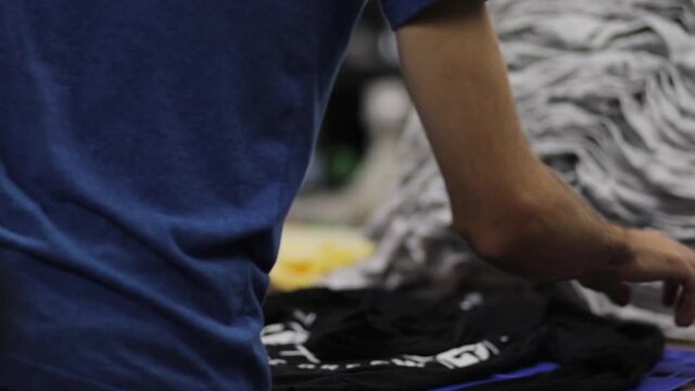 Guy folding shirts at a screen printing or retail business