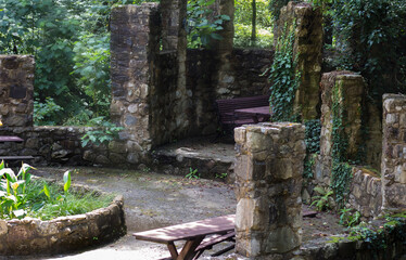 Obraz premium Wooden bench and table without people in the stone gazebo of the summer Park among the trees