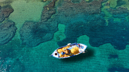 Fototapeta na wymiar Aerial drone top down photo of traditional fishing boat anchored in small picturesque fishing village of Porto Kagio, Mani Peninsula, Peloponnese, Greece
