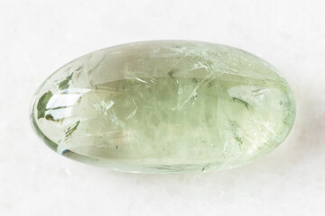 closeup of sample of natural mineral from geological collection - polished Prasiolite (green quartz) rock on white marble background from Brazil