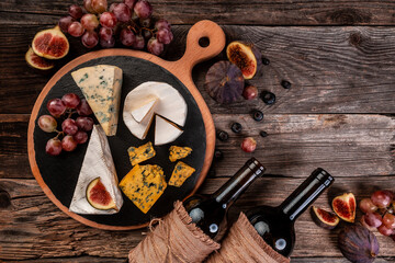 Delicious gourmet cheese, assortment of soft cheeses served with sliced sweet fresh figs and grapes on a rustic wooden background, catering, banner, menu, recipe, place for text