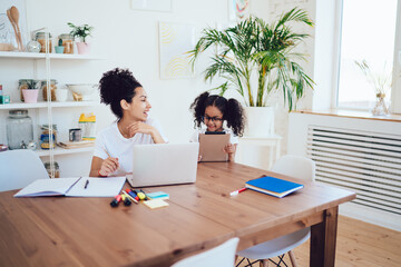 Cheerful little daughter and freelance young mother at home