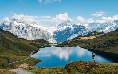 A hiker explores Lake Bachalpsee at Switzerland's Grindelwald. Location place Bachalpsee, Swiss...