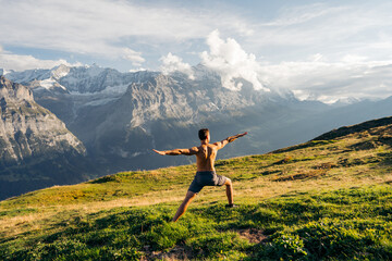 Young man doing practicing yoga at mountain in the background Eiger, a 3,967-metre mountain of the...